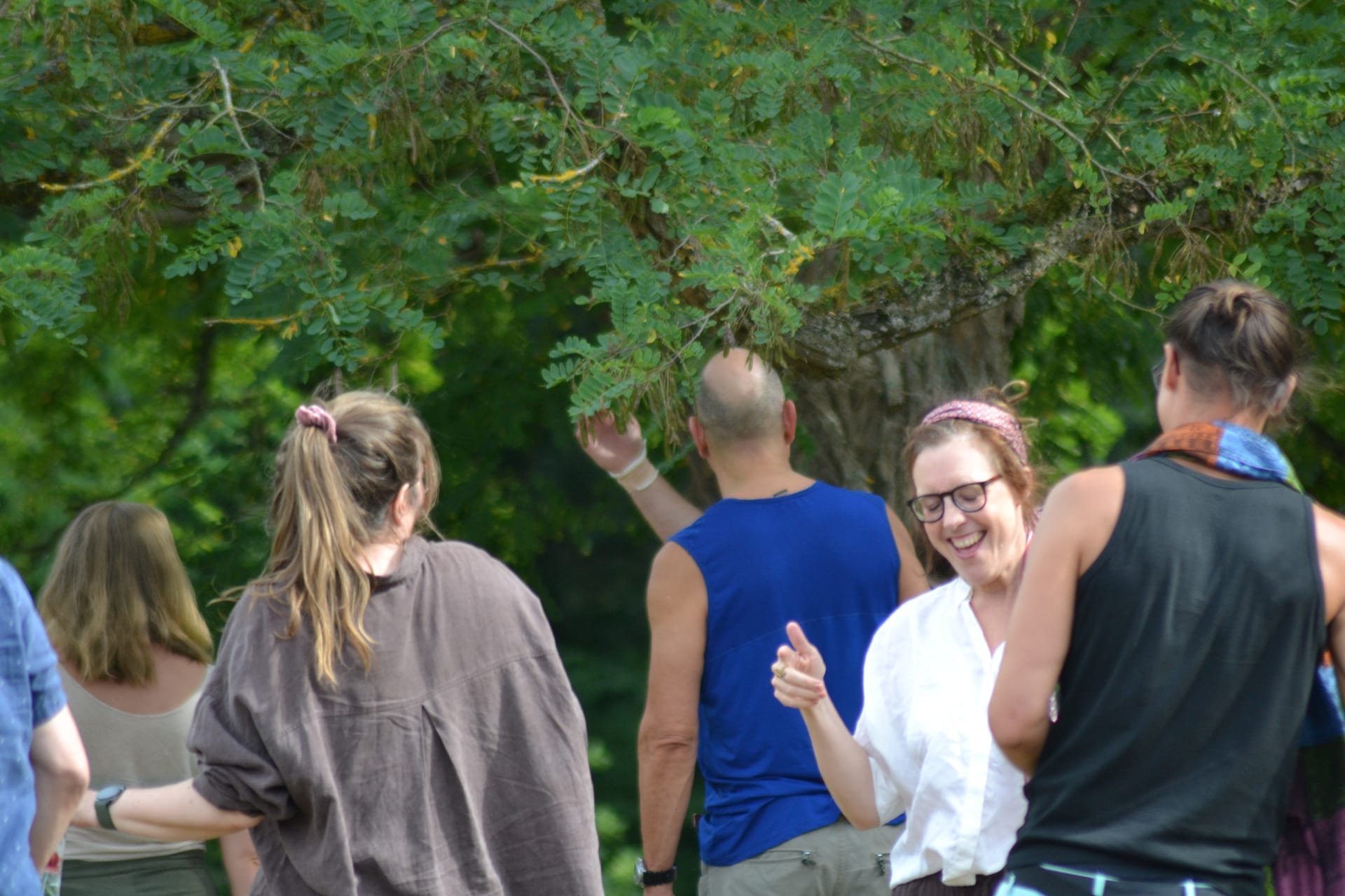 Participants dancing and laughing together under the trees in the garden