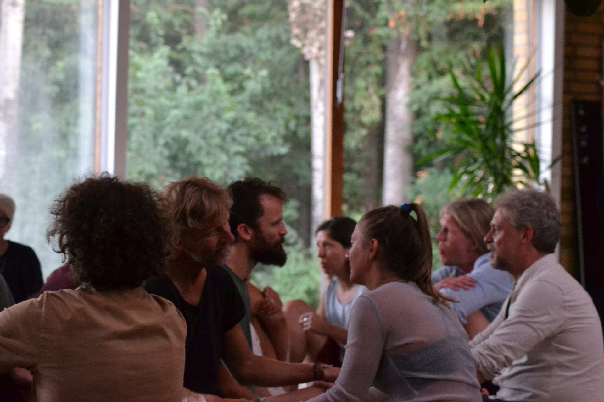 Participants sitting face to face in pairs in a sunlit room during a relational practice